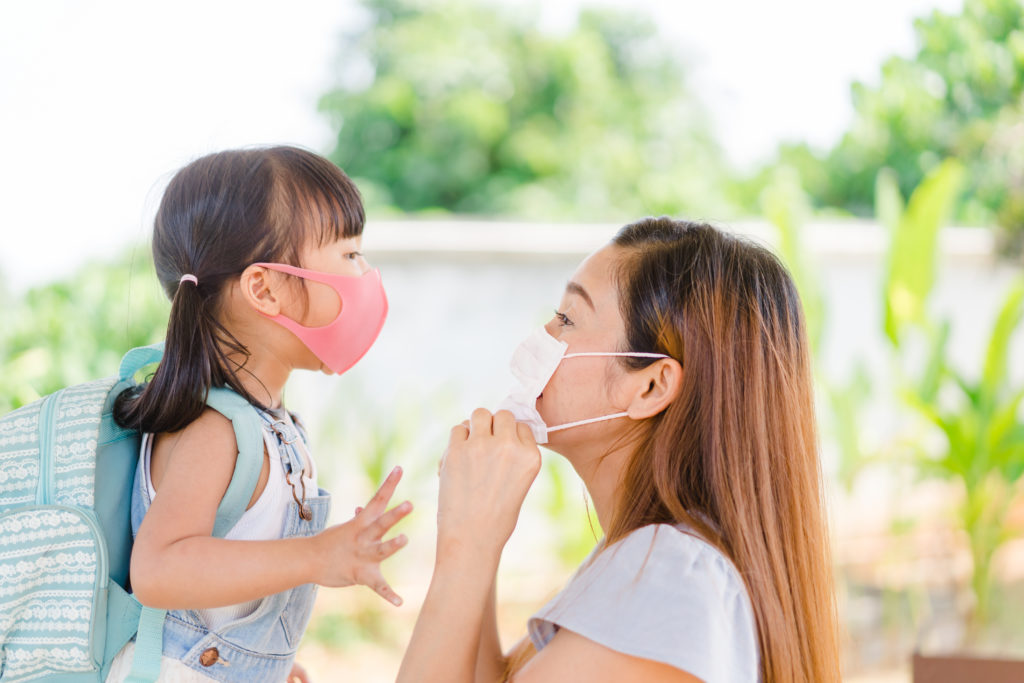 Seorang ibu dan anak menggunakan masker untuk mencegah penularan COVID-19.